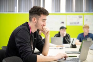 Male student in class working on a laptop