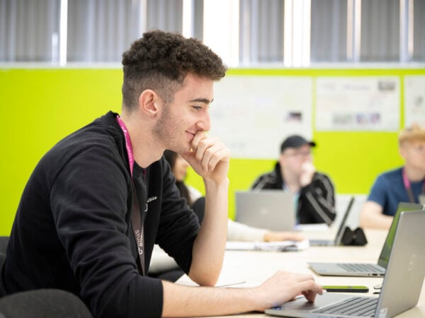 Male student in class working on a laptop