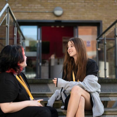 2 students sitting on steps outside a college