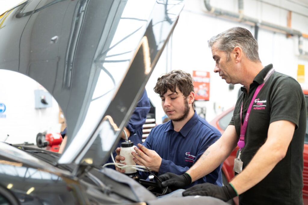 Tutor and student working on a car