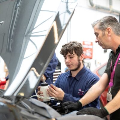Tutor and student working on a car