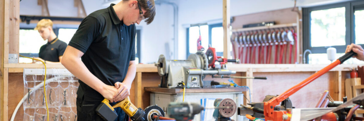 student using cutter for pipework on a workbench.