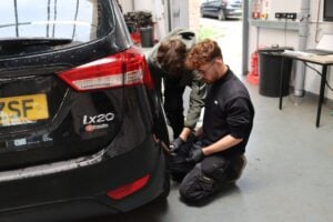Students checking the tyre on a car in an automotive garage