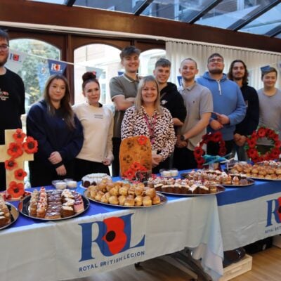 Students serving behind a table full of cakes
