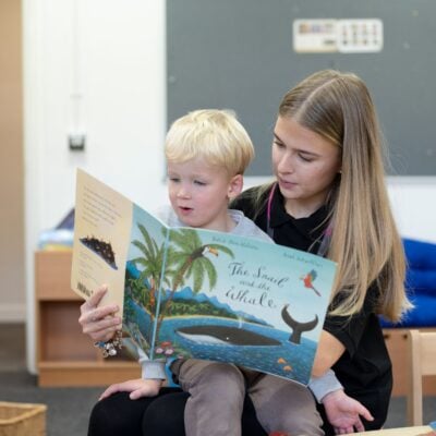 Student with little boy on her lap reading a story