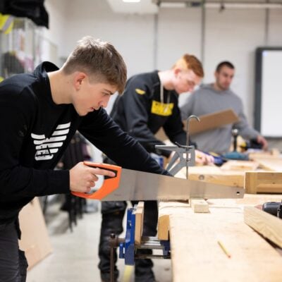 Young man sawing wood