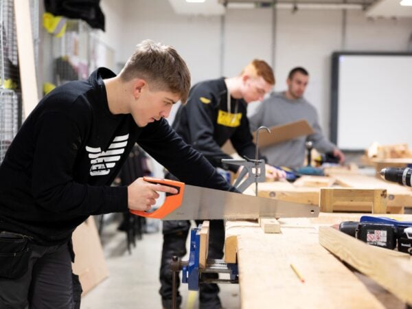 Young man sawing wood