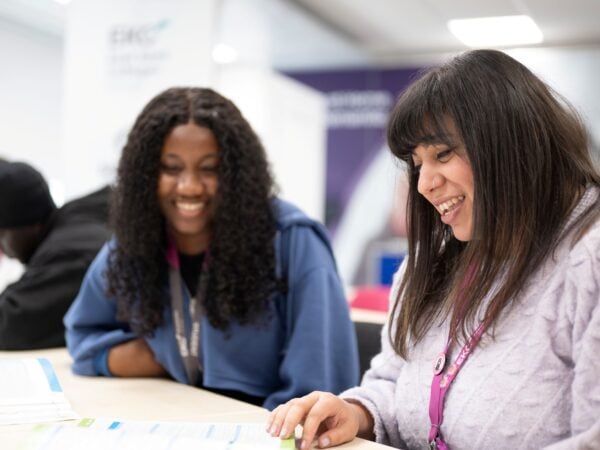 Two adult students sat looking through work