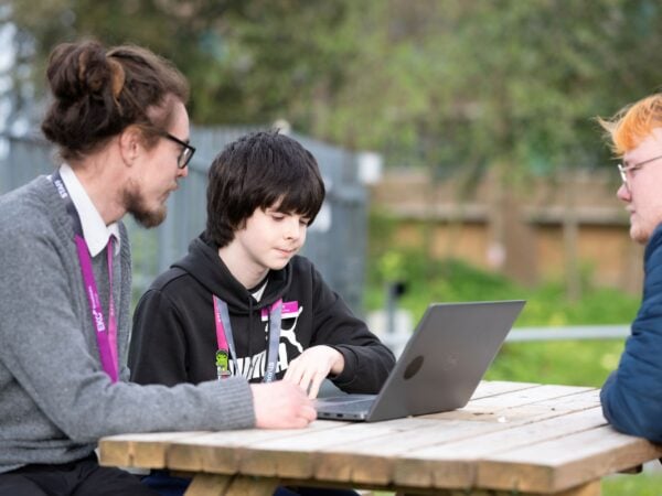 tutor sat at a picnic bench with a learner looking at a laptop