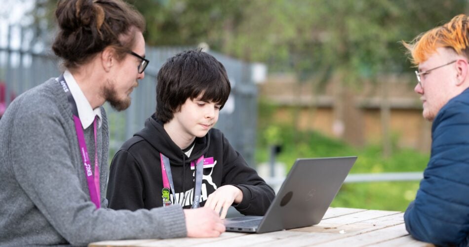tutor sat at a picnic bench with a learner looking at a laptop