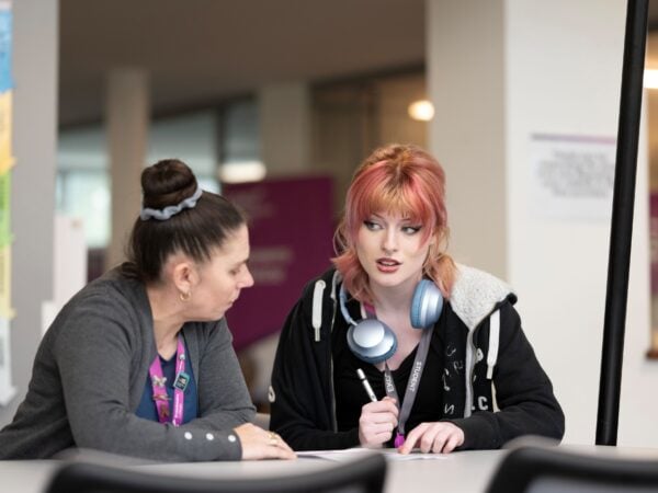 two woman sat at a desk talking