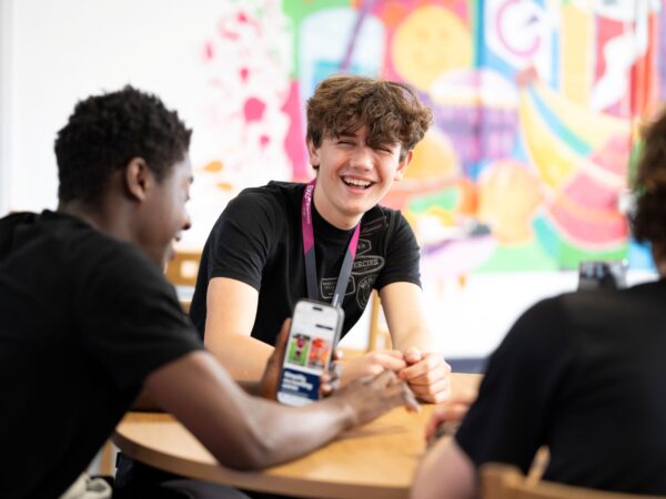 Student smiling while sat with others at a table