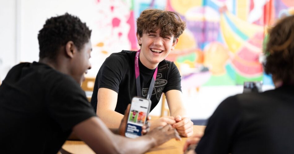 Student smiling while sat with others at a table