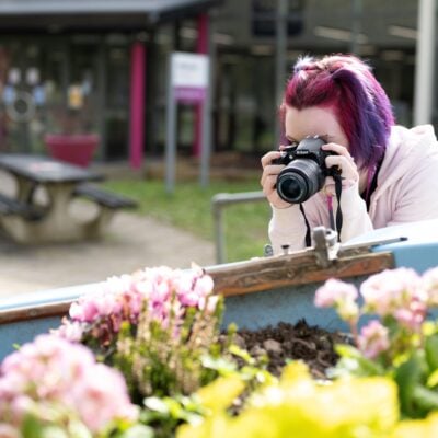 Student taking a photo of a flower