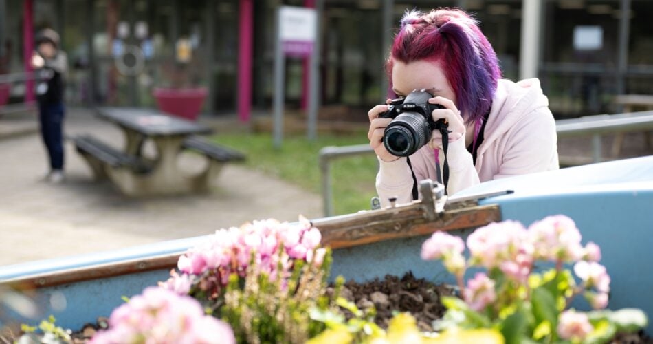 Student taking a photo of a flower