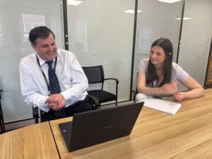 Student and mentor sat in office with a laptop