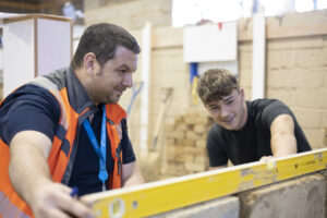 Bricklaying student learning how to level from his teacher