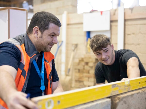 Bricklaying student learning how to level from his teacher