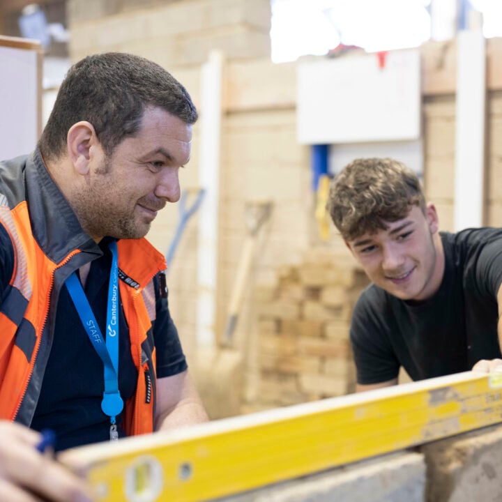 Bricklaying student learning how to level from his teacher