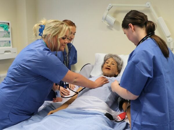 Health and Social Care students working with manikin in medical simulation suite