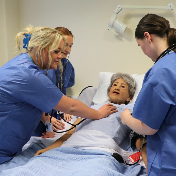 Health and Social Care students working with manikin in medical simulation suite
