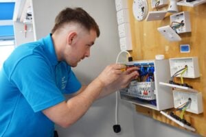 Lindan, working in the Electrical bays at the College's Electrical workshop. He is wiring sockets.