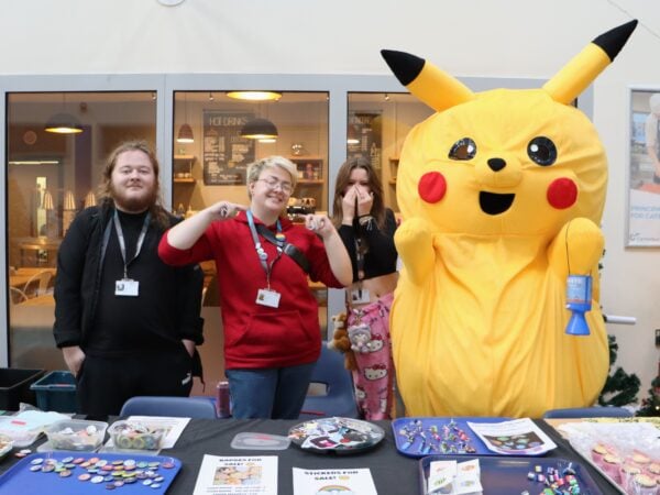 Students stood smiling at the badge stall