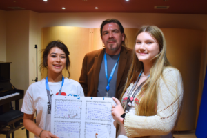 Two college students that study music pose for a photo with their lecturer