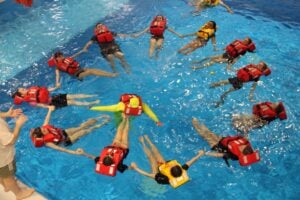 Students floating in circle in pool wearing life jackets