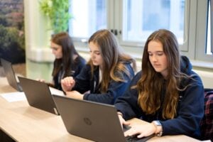 three students look at three laptops