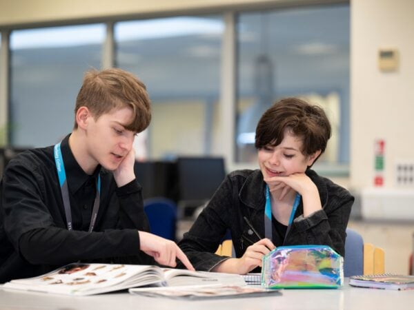 two students look at a book at college