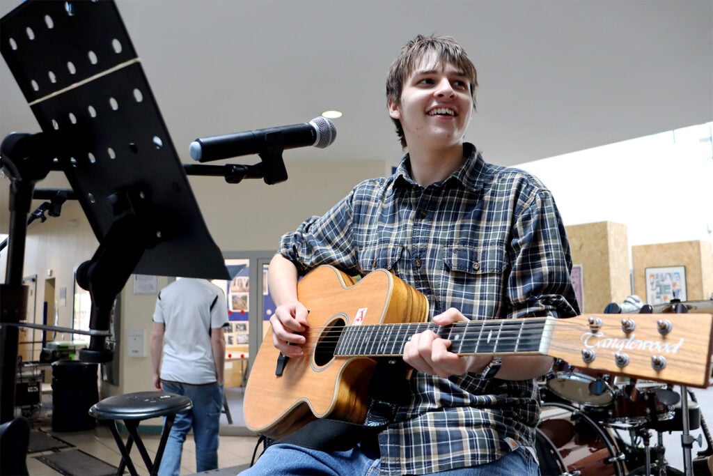 student playing music on guitar at freshers fair