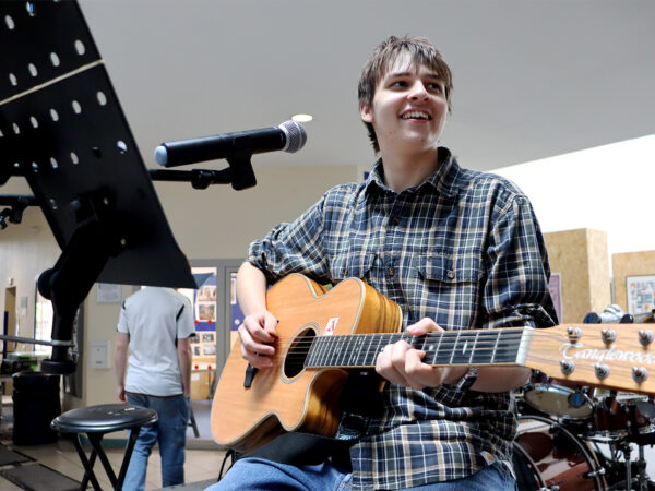 student playing music on guitar at freshers fair