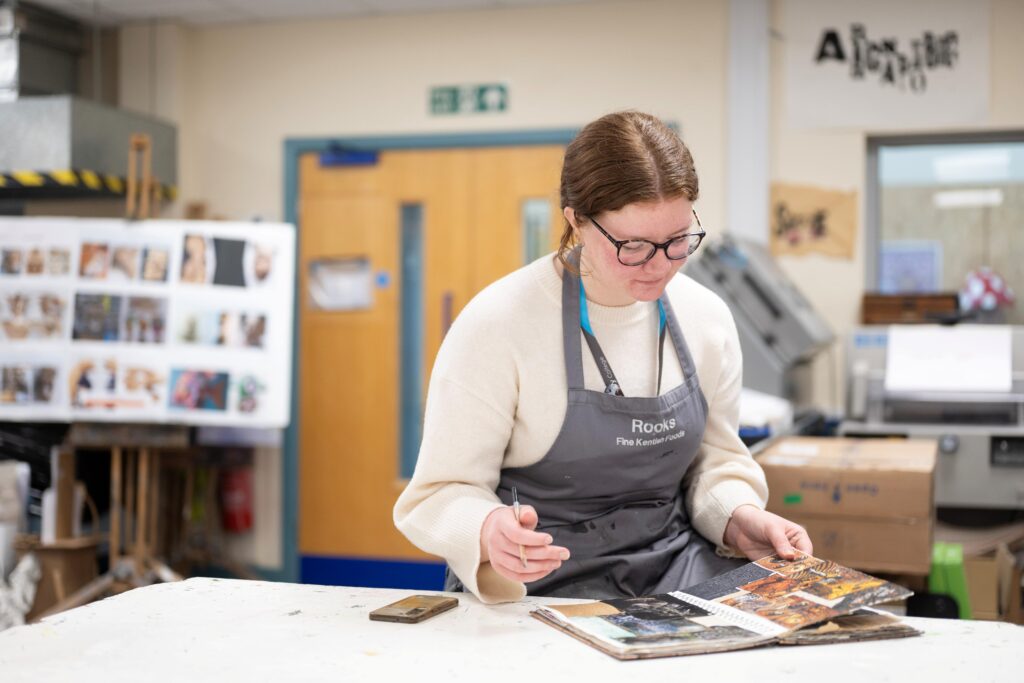 art and design student looking at a sketchbook portfolio
