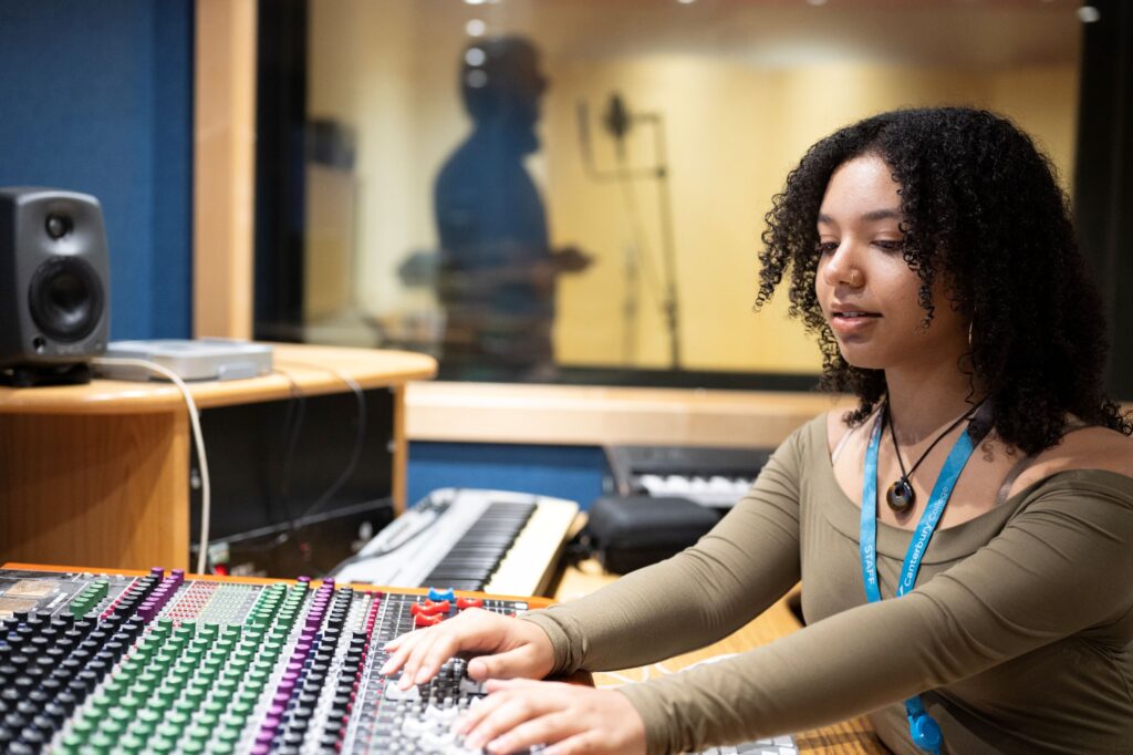 Student using mixing deck in recording studio