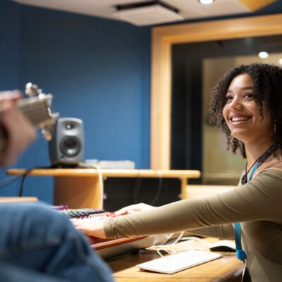 student checking sound on a soundboard in the music studio.
