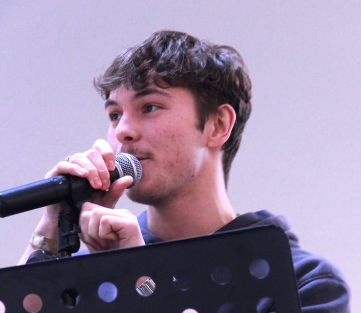 Student on stage, singing into a microphone