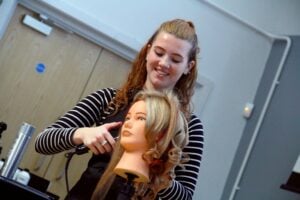 A lady styling the hair of a sally head, hairdressing doll