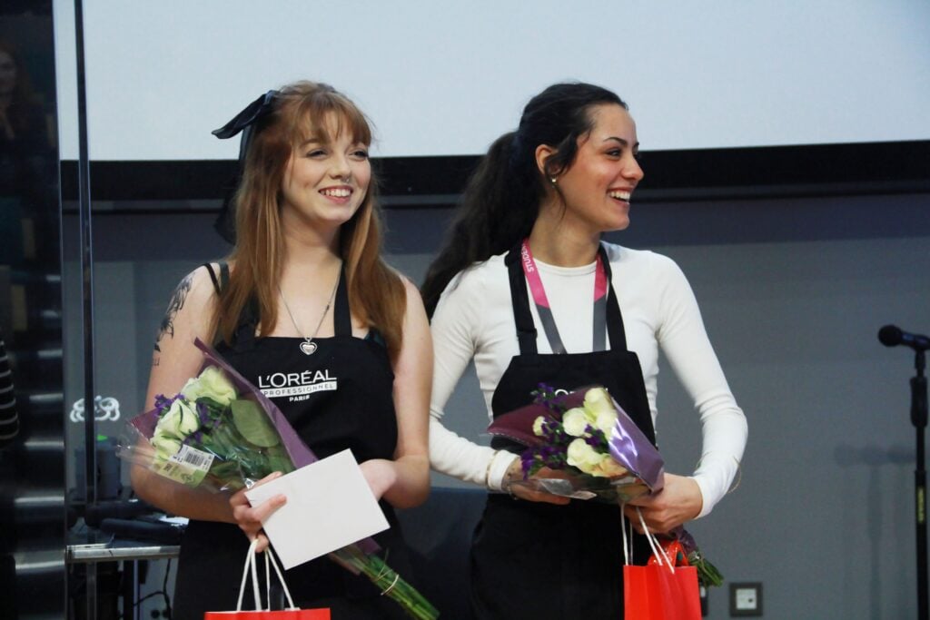 Two hairdressing students holding flowers
