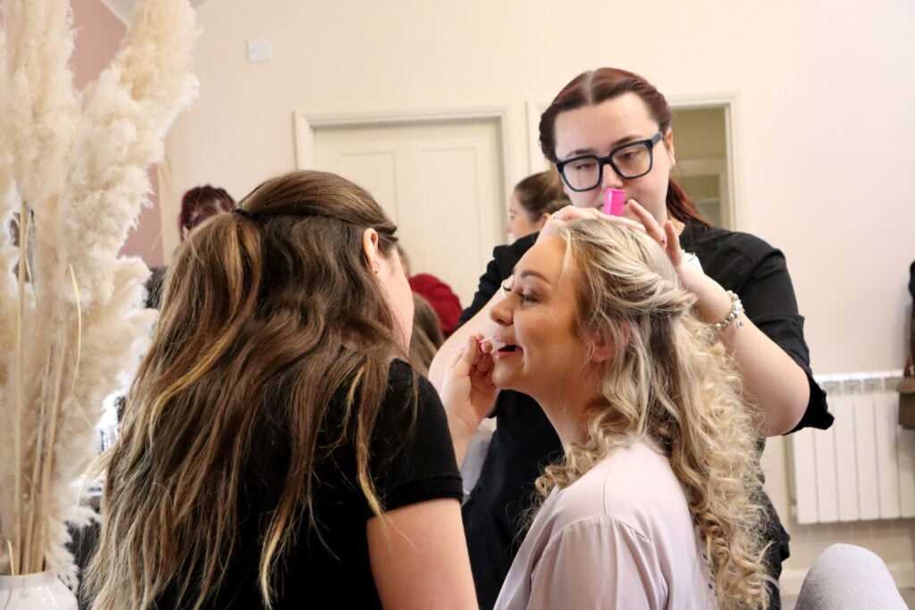 A model having her hair pinned and lipstick put on