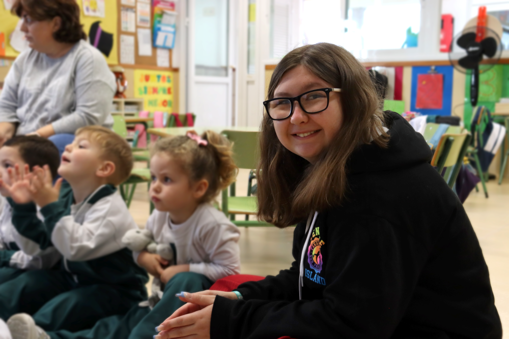 student sat with young children in a classroom