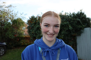 Young lady in blue jumper standing outside smiling at the camera