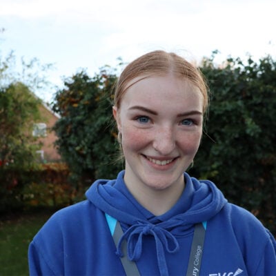 Young lady in blue jumper standing outside smiling at the camera