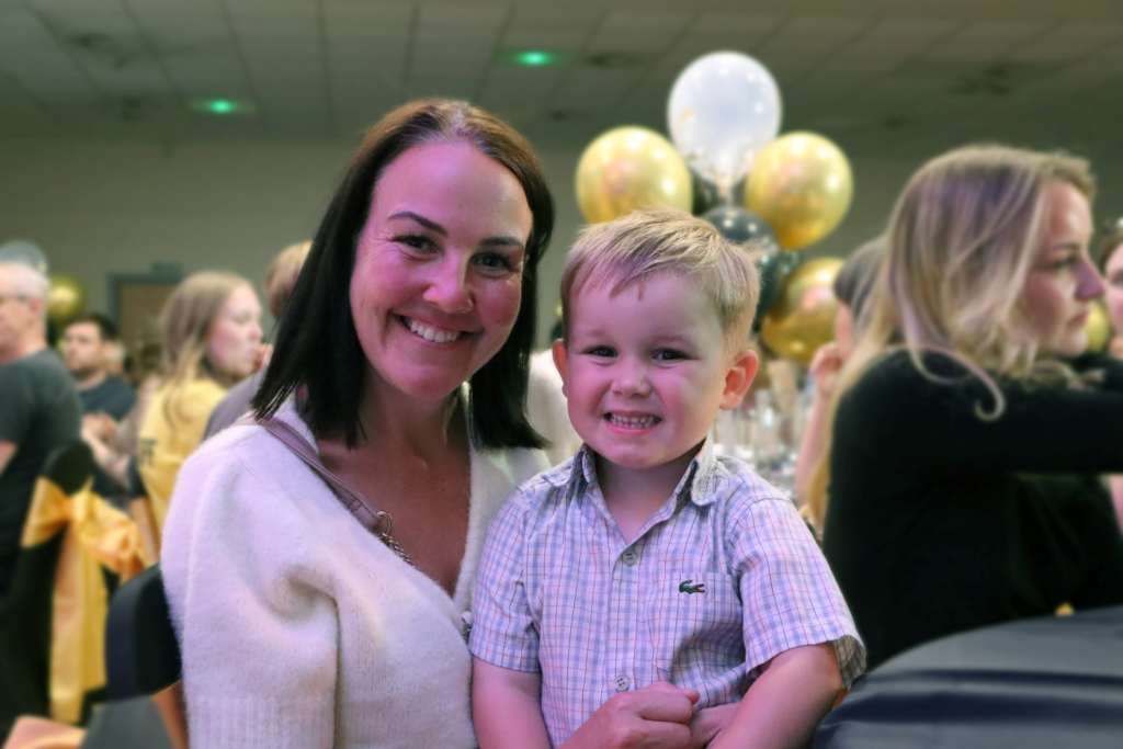 Lady holding grandson - both smiling at the camera.