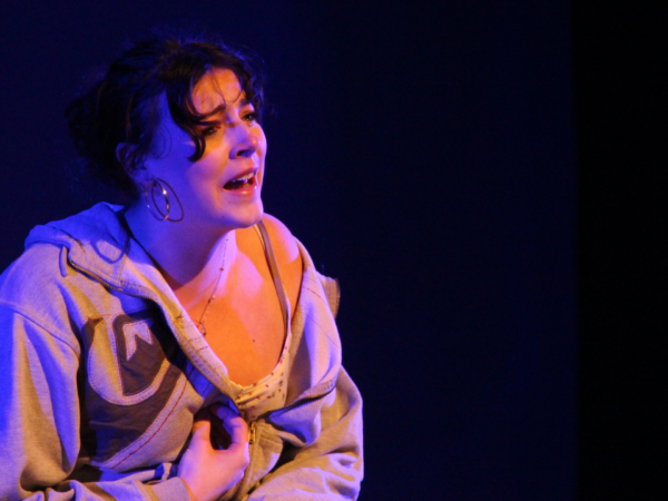 students acting on stage, crying, wearing a pinkoutfit.