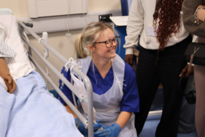 T Level Health student smiling as she demonstrates how to interact with the simulation dolls