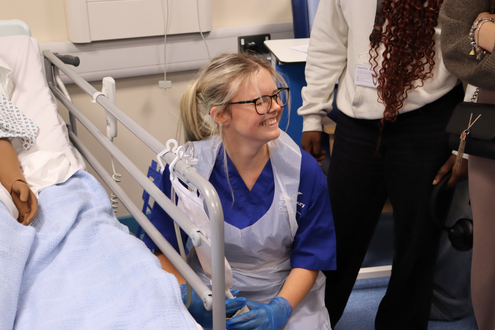 T Level Health student smiling as she demonstrates how to interact with the simulation dolls
