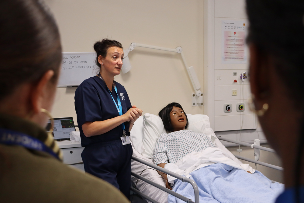Health tutor standing next to simulation doll