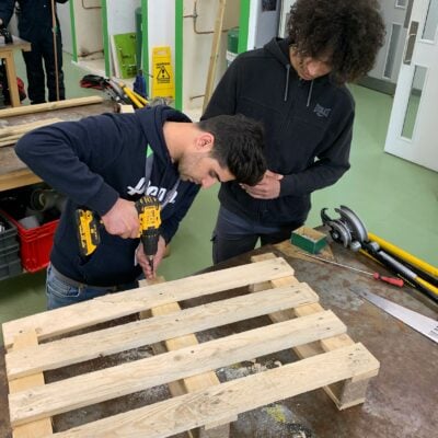 Students sawing wooden pallets to create bee hotels