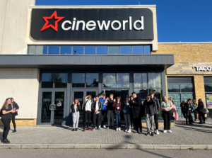 A group of students standing outside the cinema Cineworld looking at the camera on a sunny day.